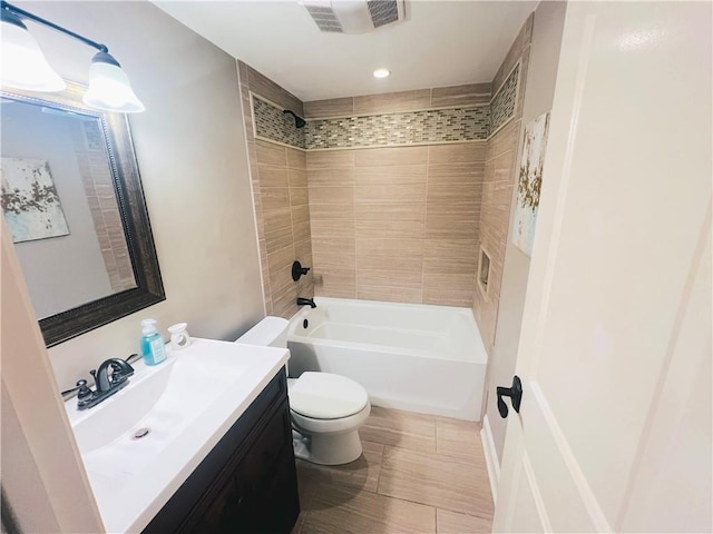 full bathroom featuring tiled shower / bath, vanity, and toilet