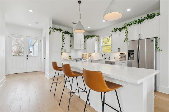 kitchen with sink, hanging light fixtures, a kitchen island, decorative backsplash, and white cabinets