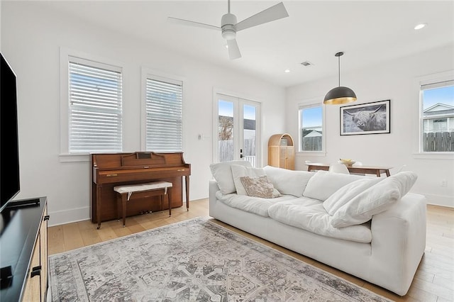 living room featuring french doors, plenty of natural light, and light wood-type flooring