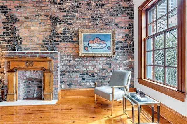 living area with brick wall and light hardwood / wood-style flooring