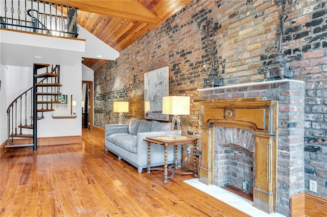 living room with light hardwood / wood-style flooring, beam ceiling, high vaulted ceiling, a brick fireplace, and wooden ceiling