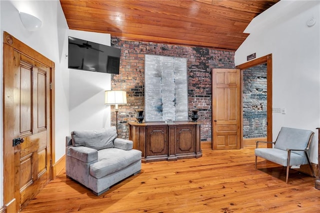 sitting room with vaulted ceiling, wooden ceiling, brick wall, and light wood-type flooring