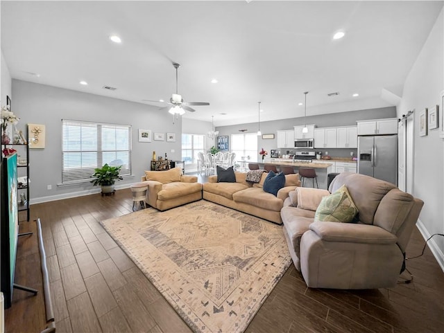 living room with a barn door, dark hardwood / wood-style floors, and ceiling fan