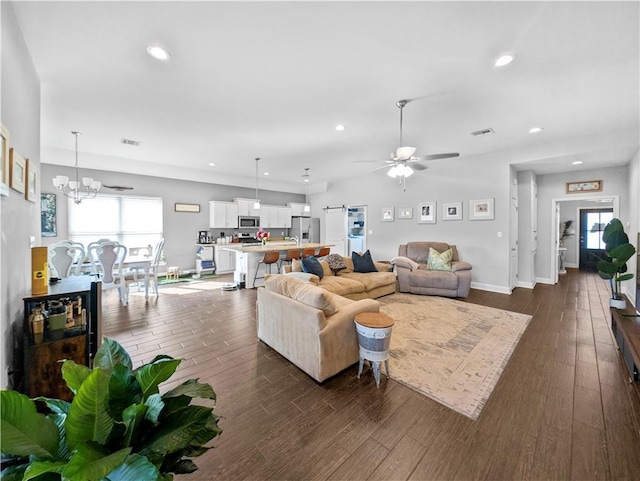 living room with dark hardwood / wood-style floors and ceiling fan with notable chandelier