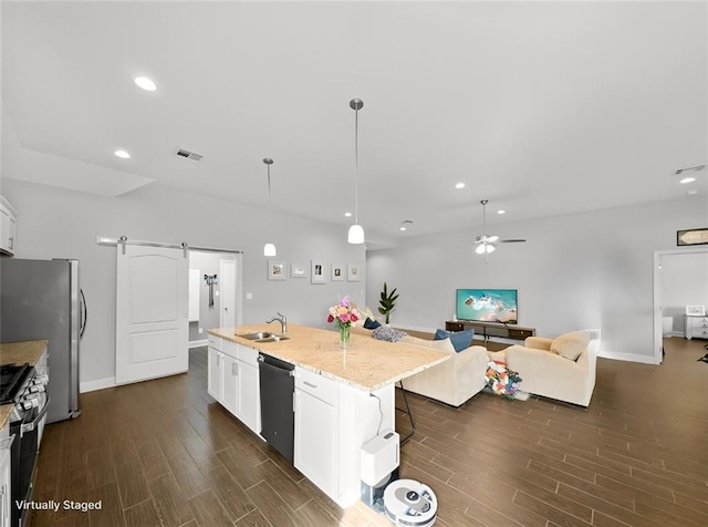 kitchen with decorative light fixtures, white cabinetry, an island with sink, dishwashing machine, and a barn door