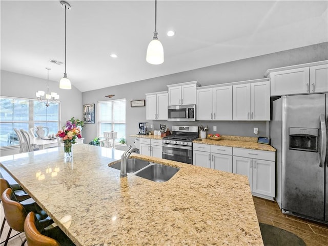 kitchen featuring white cabinetry, sink, stainless steel appliances, and hanging light fixtures