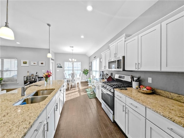 kitchen with stainless steel appliances, white cabinetry, sink, and pendant lighting