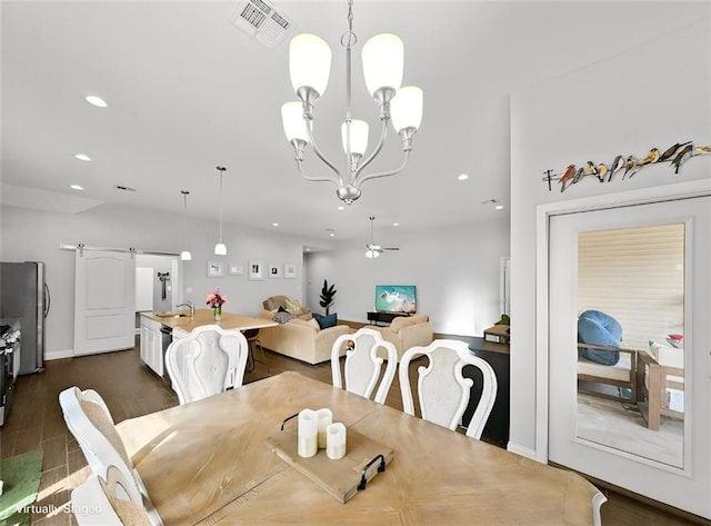 dining area featuring a barn door, sink, ceiling fan with notable chandelier, and dark hardwood / wood-style flooring