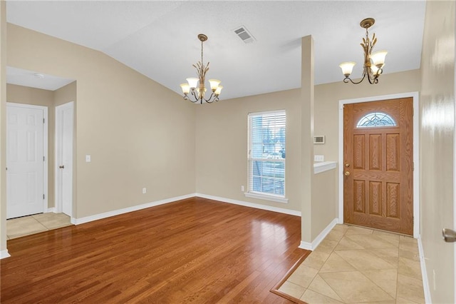 entrance foyer with plenty of natural light, light wood-type flooring, lofted ceiling, and an inviting chandelier