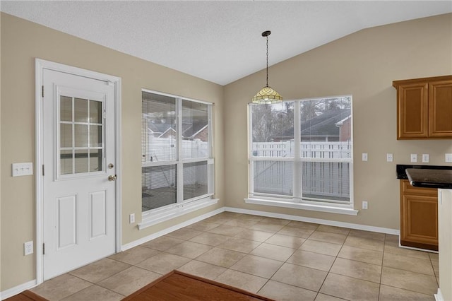 unfurnished dining area featuring vaulted ceiling and light tile patterned floors