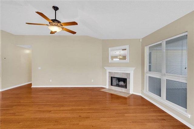 unfurnished living room with lofted ceiling, a tile fireplace, light hardwood / wood-style floors, and ceiling fan