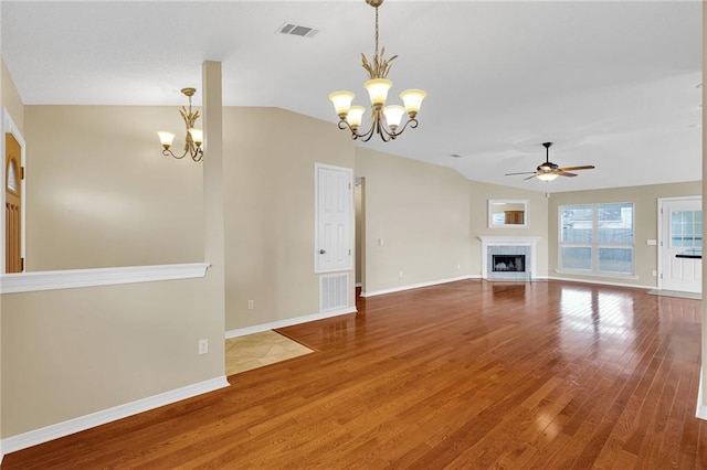 unfurnished living room with ceiling fan with notable chandelier, wood-type flooring, and vaulted ceiling