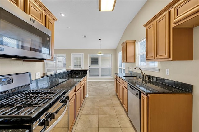 kitchen featuring appliances with stainless steel finishes, decorative light fixtures, sink, dark stone counters, and light tile patterned floors