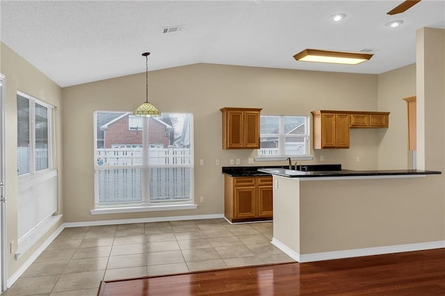 kitchen with pendant lighting, light tile patterned floors, vaulted ceiling, and plenty of natural light