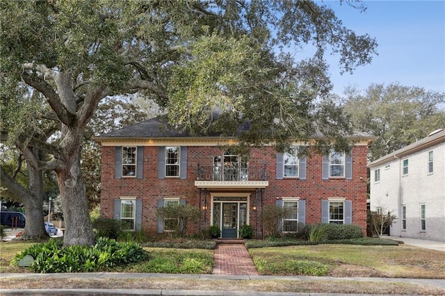 view of front of house with a front yard and a balcony