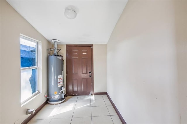 entryway featuring lofted ceiling, plenty of natural light, water heater, and light tile patterned floors