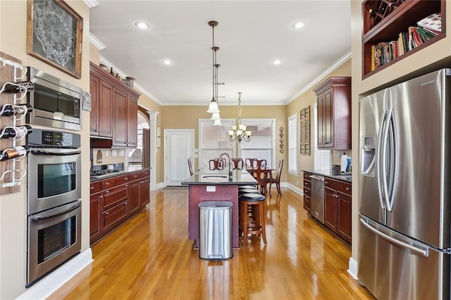 kitchen featuring a breakfast bar, crown molding, a chandelier, pendant lighting, and stainless steel appliances