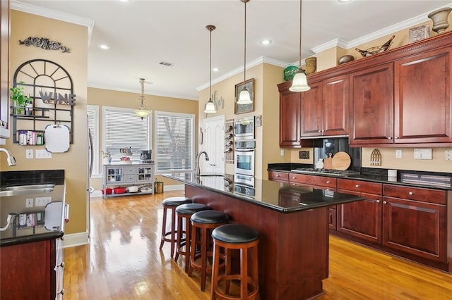 kitchen featuring appliances with stainless steel finishes, sink, a breakfast bar area, hanging light fixtures, and a center island with sink