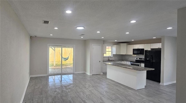 kitchen with sink, black appliances, a kitchen island, decorative backsplash, and white cabinets