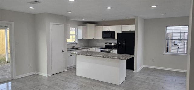 kitchen with stone counters, backsplash, a center island, black appliances, and white cabinets