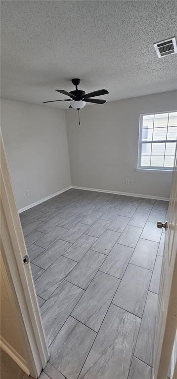 empty room featuring a textured ceiling and ceiling fan