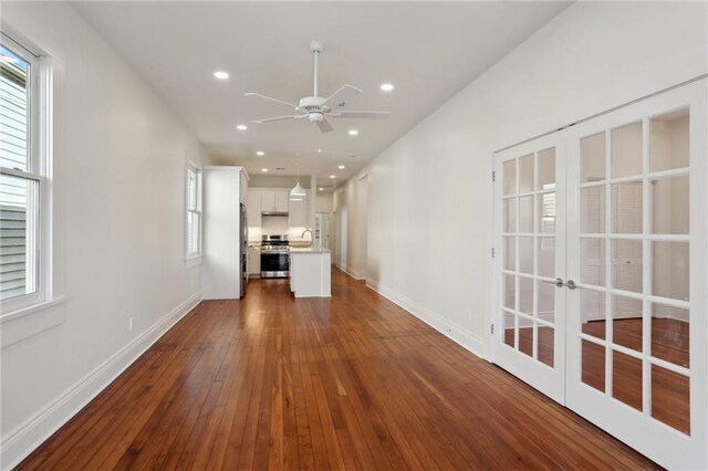 unfurnished living room with dark hardwood / wood-style flooring, sink, french doors, and ceiling fan