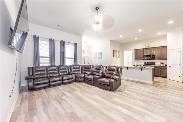 living room with ceiling fan and light hardwood / wood-style flooring