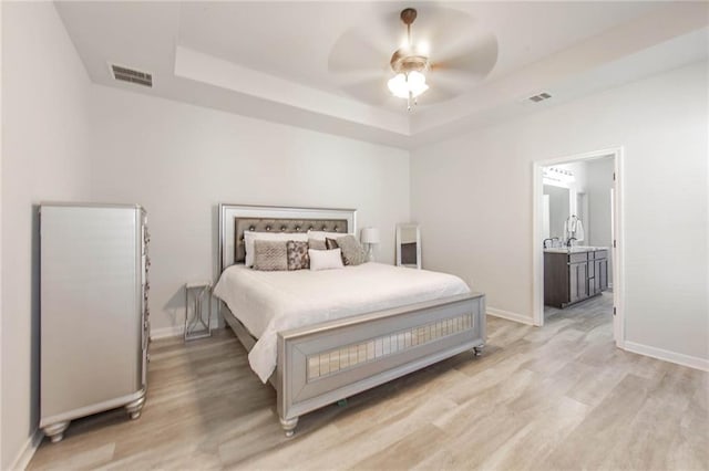 bedroom with a raised ceiling, ceiling fan, and light wood-type flooring