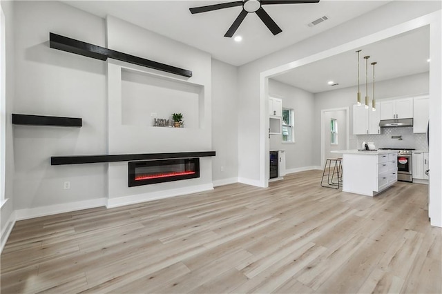 unfurnished living room featuring light hardwood / wood-style floors, beverage cooler, and ceiling fan