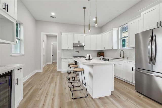 kitchen featuring stainless steel refrigerator, white cabinetry, beverage cooler, and a kitchen island