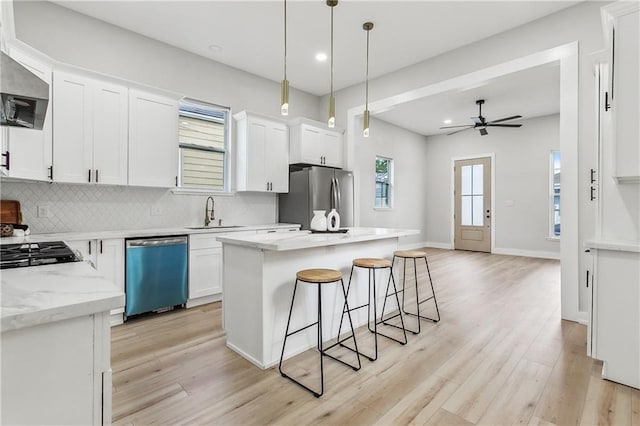 kitchen with pendant lighting, sink, appliances with stainless steel finishes, white cabinetry, and a center island