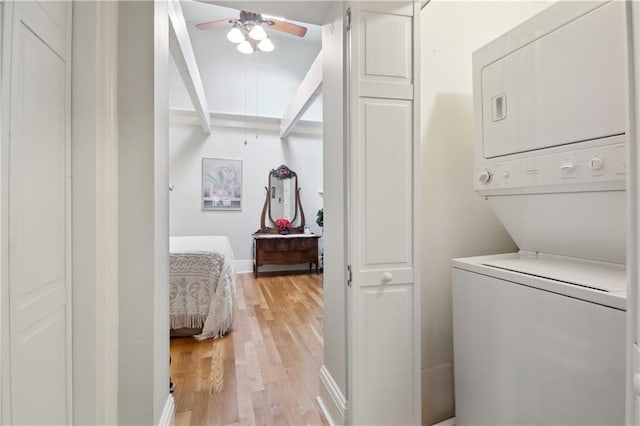 clothes washing area featuring stacked washer / drying machine, light hardwood / wood-style flooring, and ceiling fan