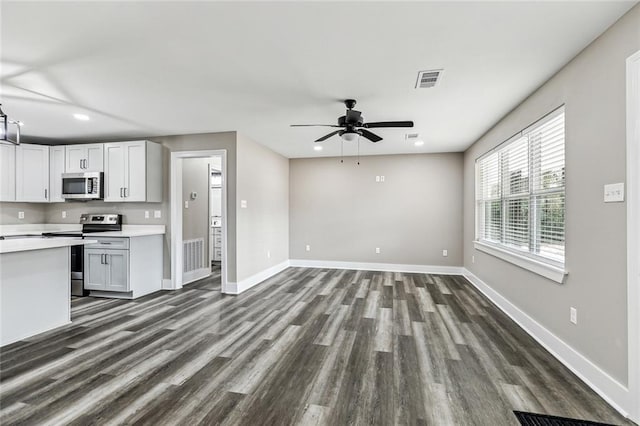 kitchen with stainless steel appliances, ceiling fan, white cabinets, and dark hardwood / wood-style flooring