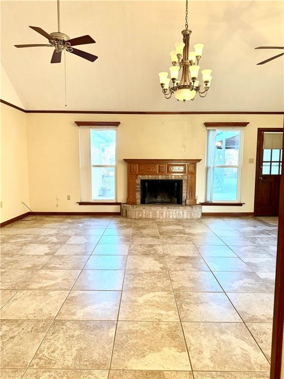 unfurnished living room with a brick fireplace, ceiling fan, and a high ceiling