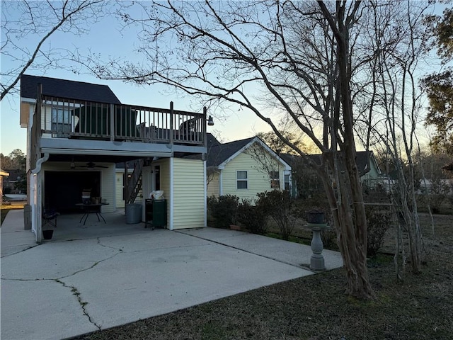 back house at dusk featuring a wooden deck and a garage