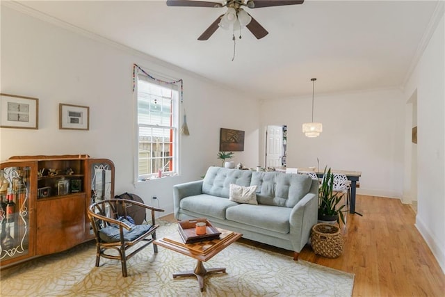 living room with crown molding, ceiling fan, and light wood-type flooring