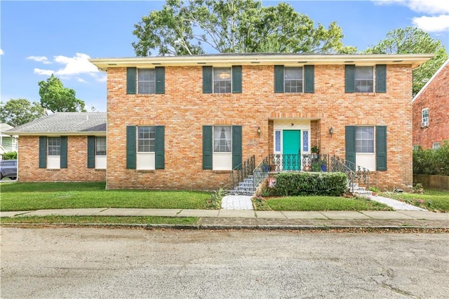 colonial inspired home featuring brick siding and a front lawn