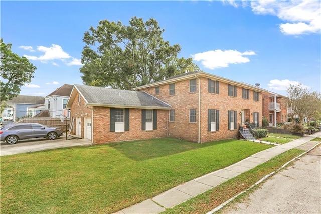 colonial house with a front yard, brick siding, driveway, and an attached garage