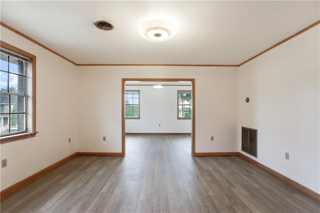 spare room featuring baseboards, crown molding, visible vents, and wood finished floors