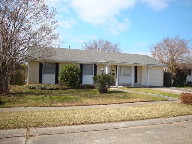 ranch-style house featuring a shingled roof, a front yard, and fence