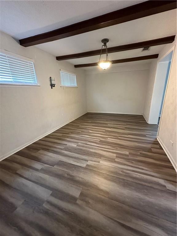 interior space with beamed ceiling, dark wood-style flooring, visible vents, and baseboards