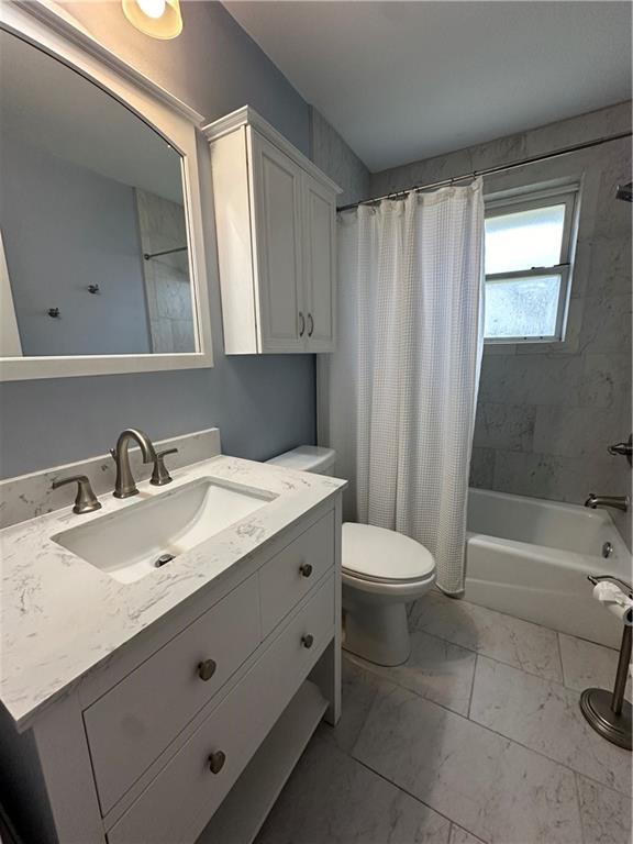 full bathroom with toilet, marble finish floor, shower / tub combo with curtain, and vanity