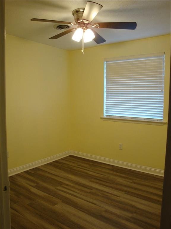 spare room with ceiling fan, baseboards, and dark wood-type flooring