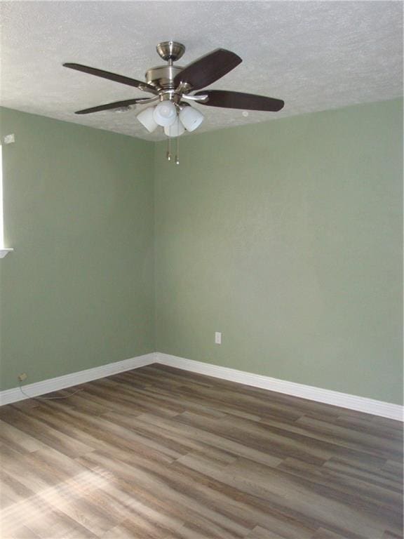 unfurnished room with a textured ceiling, wood finished floors, and baseboards