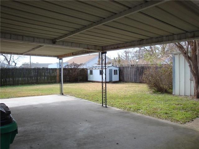 view of patio / terrace featuring a carport, a storage unit, an outdoor structure, and a fenced backyard