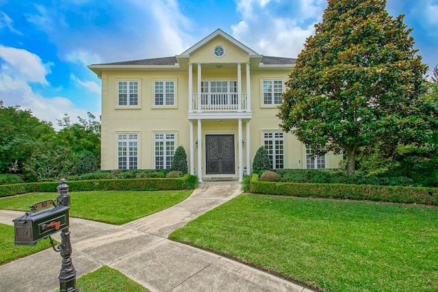 view of front of house with a balcony and a front yard