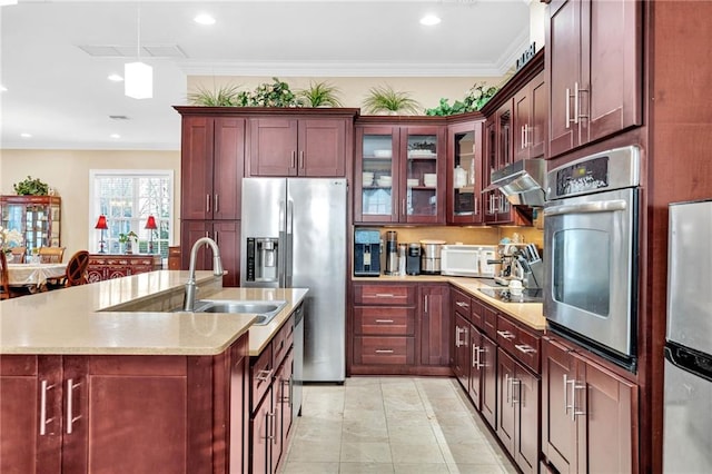 kitchen featuring sink, hanging light fixtures, ornamental molding, an island with sink, and stainless steel appliances