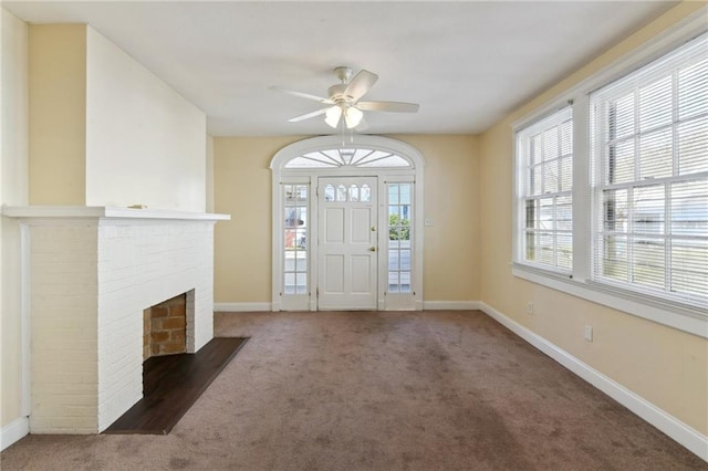 foyer with a fireplace, ceiling fan, and dark colored carpet