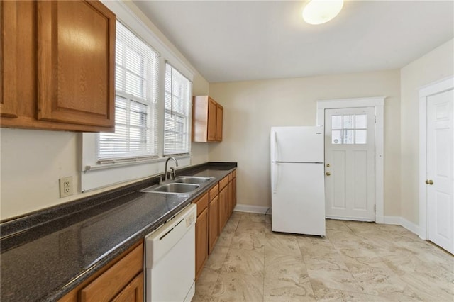 kitchen with dark stone countertops, sink, and white appliances