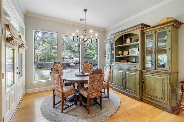 dining space with a notable chandelier, ornamental molding, and light wood-type flooring